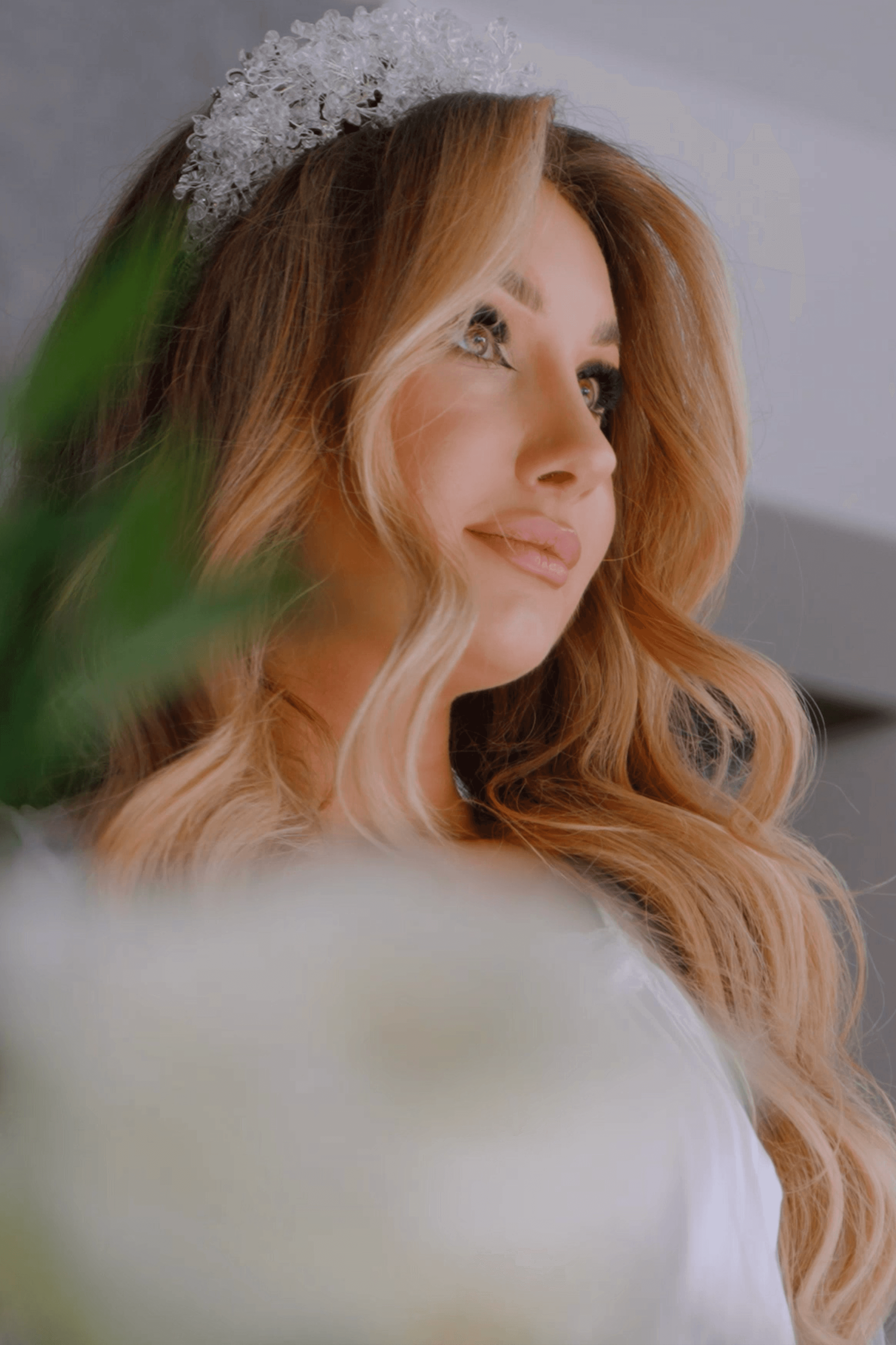 A couple in wedding attire shares a romantic kiss on a leafy path by a tranquil river.