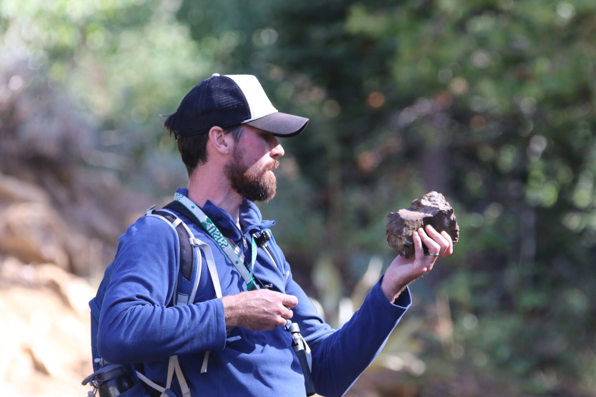 Geoscientist Graham Lederer uses a hand lens to examine tungsten ore