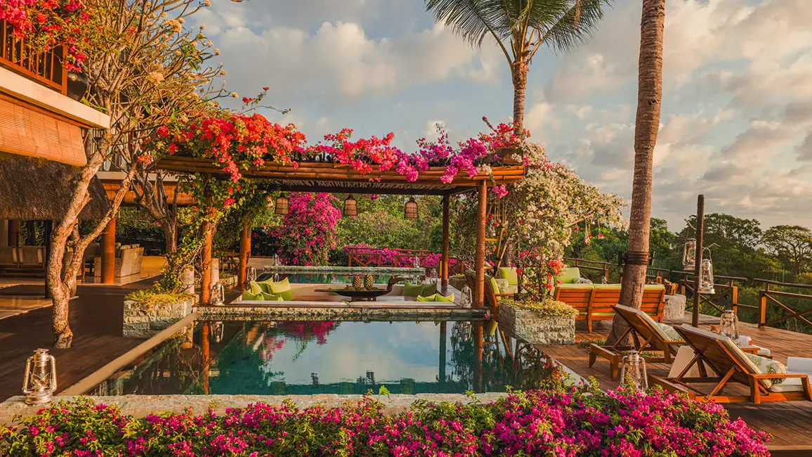 Ein luxuriöser Pool mit Blick auf eine malerische Landschaft, umgeben von bunten Blumen und Holzmöbeln.
