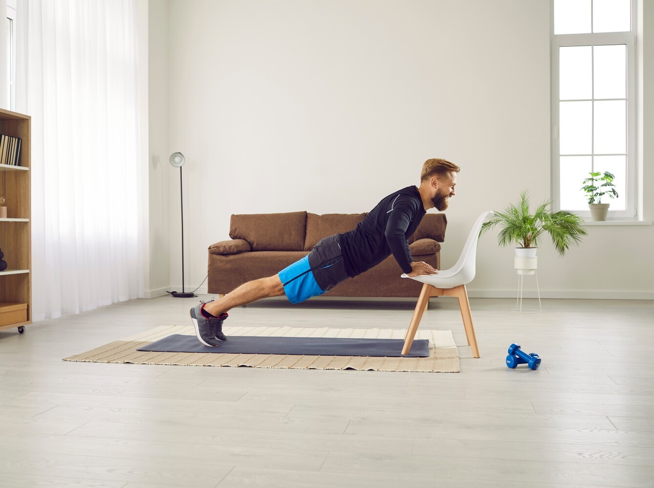 fit man doing chair push-ups as part of his routine of low-impact chair exercises for weight loss at home in his living room