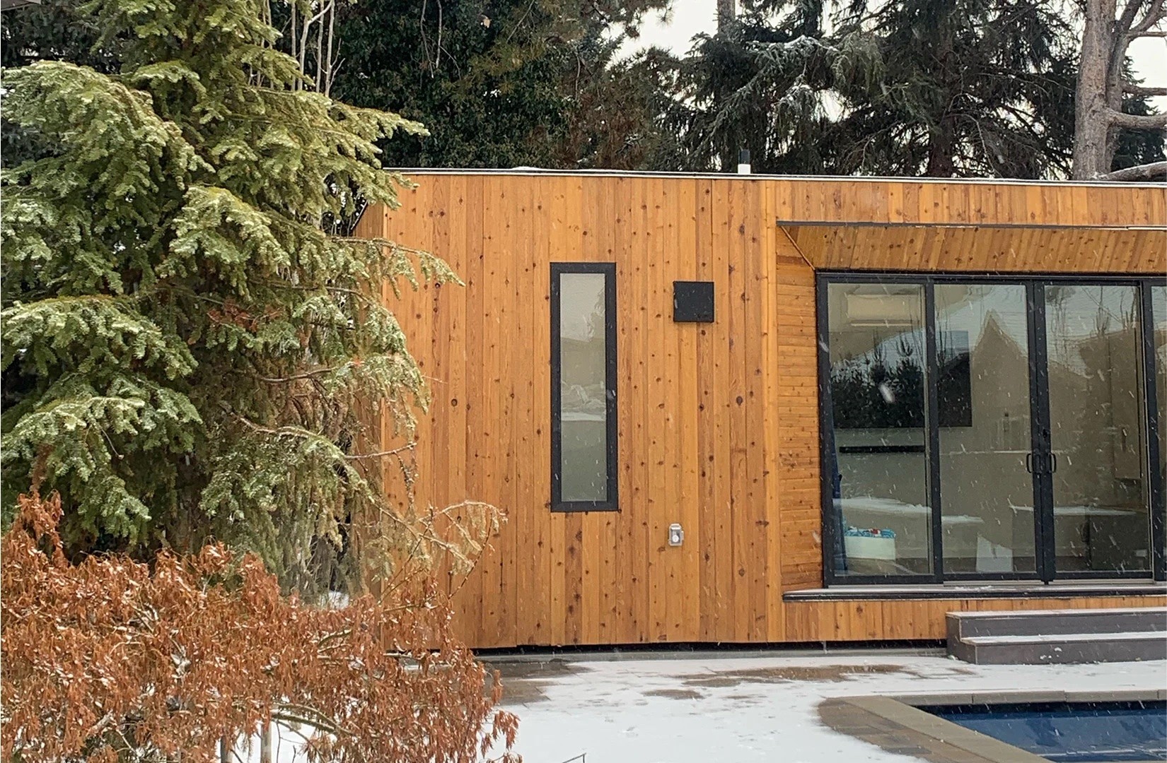 Wooden modular home with large windows in the winter.