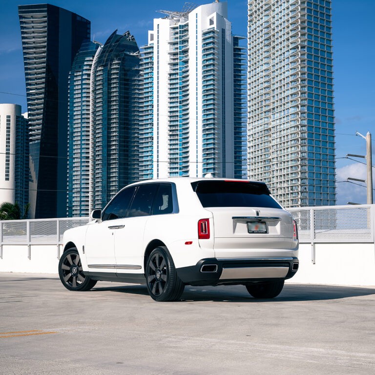 Rear 3/4 view of a white Rolls-Royce Cullinan, showcasing its iconic design and presence.