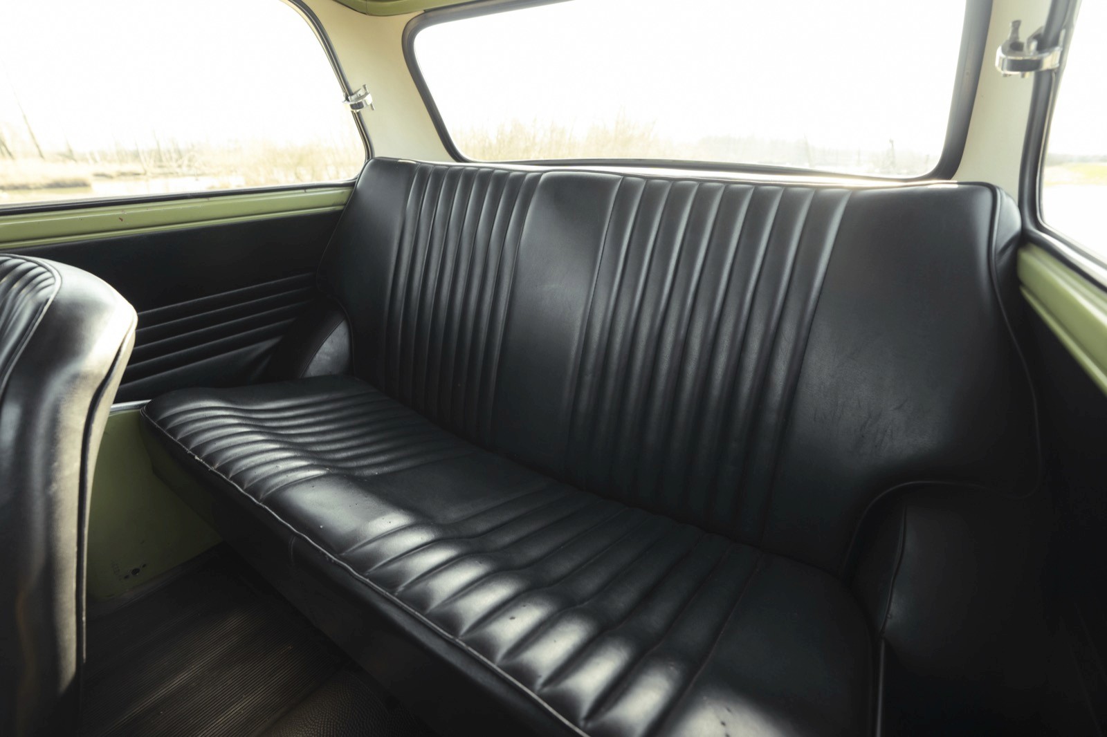 Interior view of a vintage car's back seat, featuring a sleek black leather upholstery.