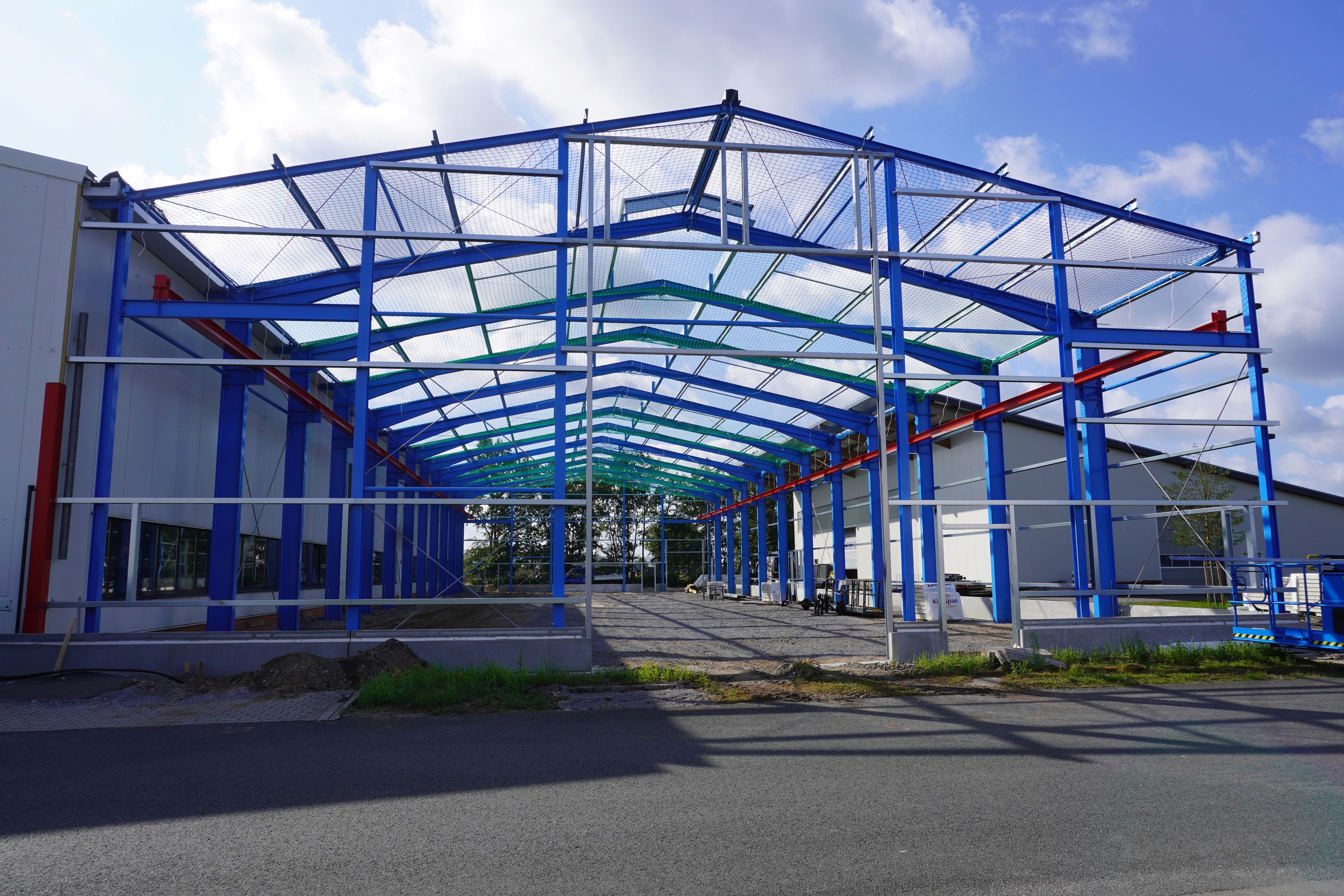Stahlkonstruktion einer Lagerhalle im Bau. Blaues Metallgerüst mit Dach. Neubau.