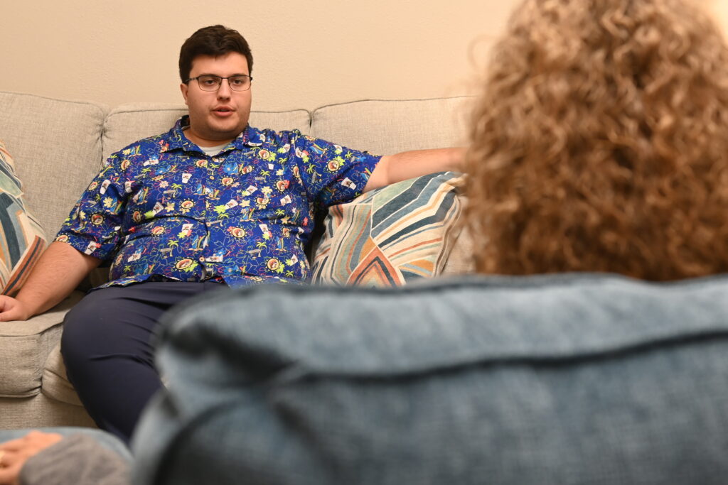 A man talking to a person sitting on a couch
