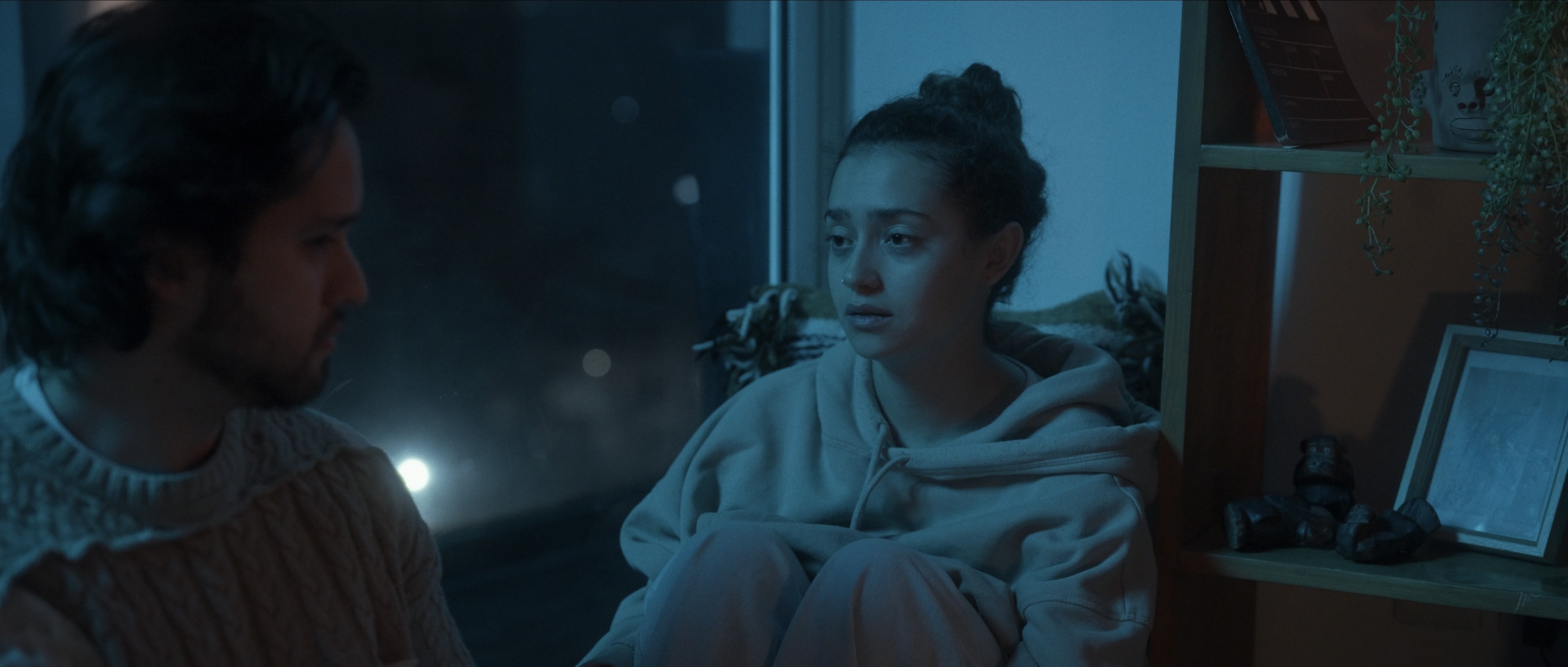 Woman in a light suit sitting thoughtfully against a terracotta wall