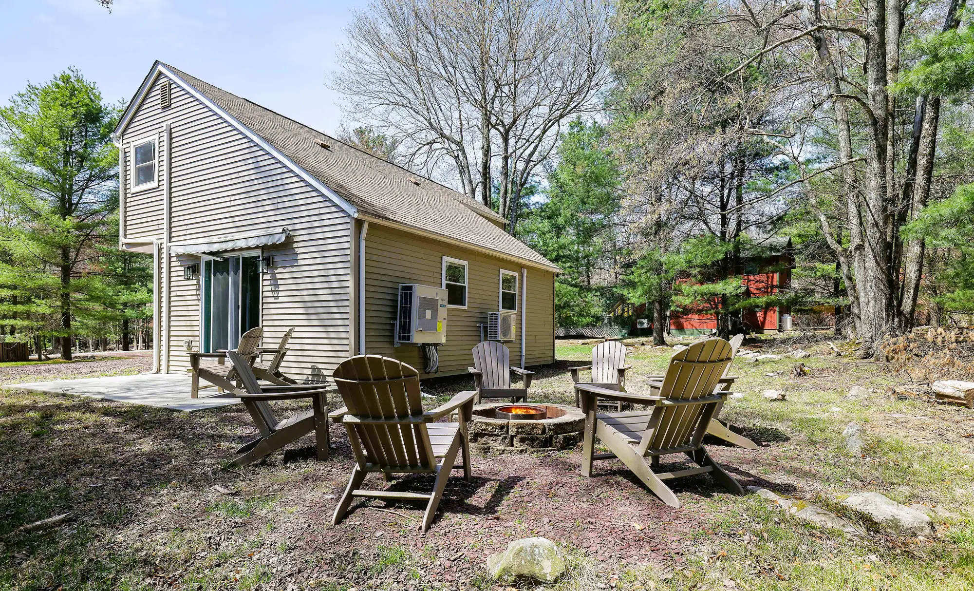 Side yard with Adirondack chairs around a fire pit at Divine on Lupine, Lake Harmony, PA