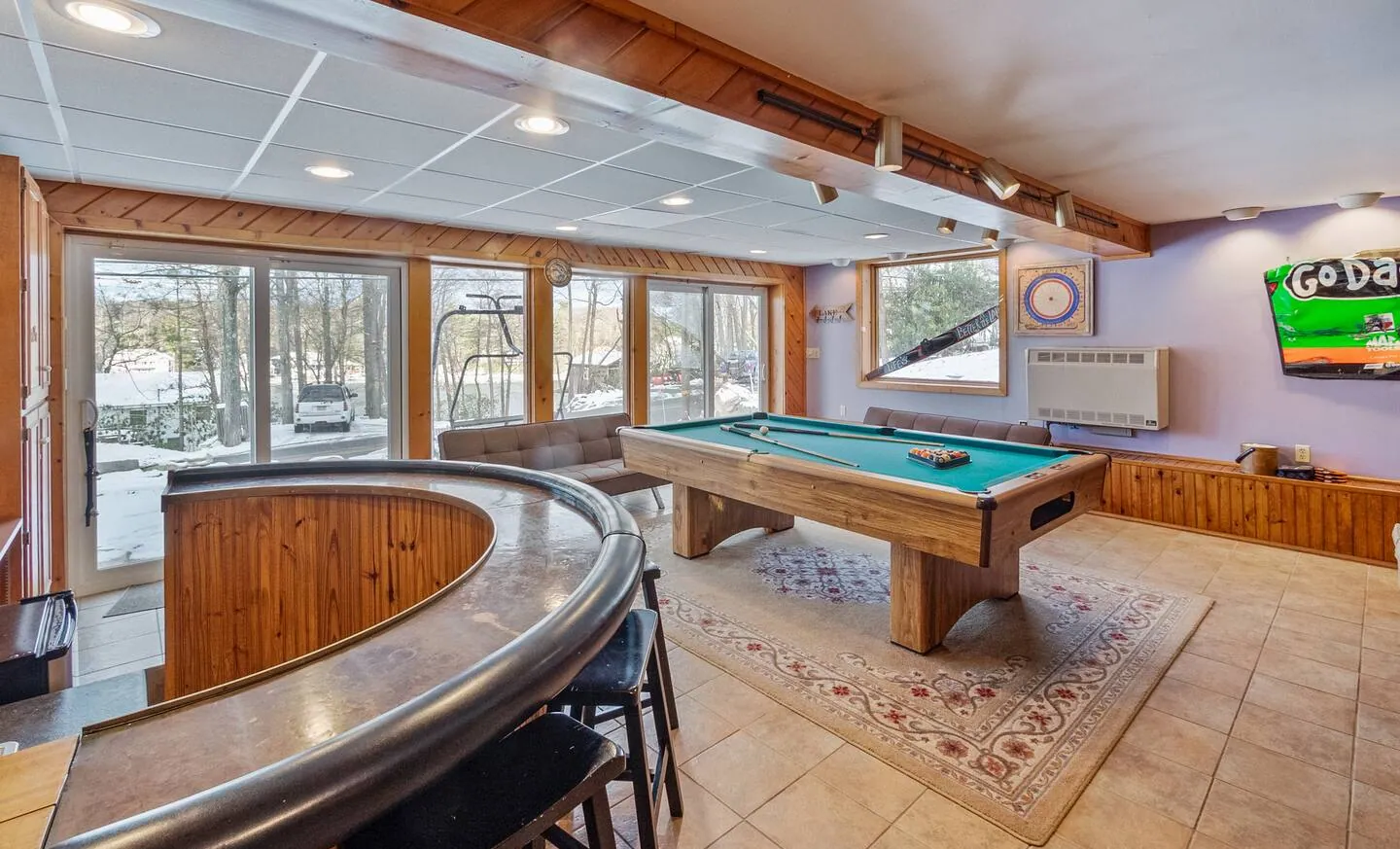 Lower level game room with curved bar, pool table and lake-facing windows at Repeat Retreat