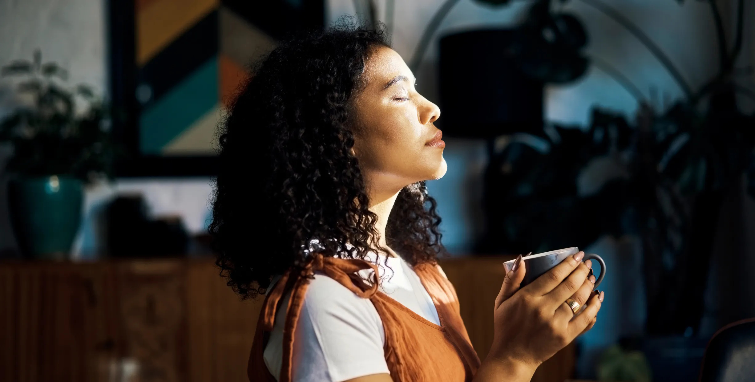 Photo of a woman with her eyes closed and holding a mug with her hands