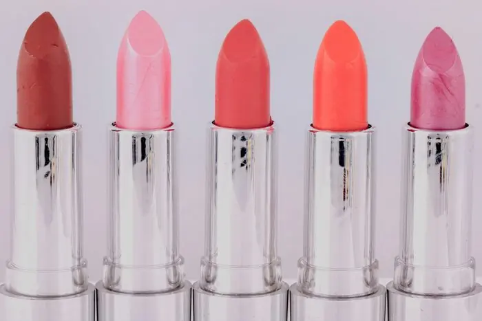 Five lipstick bullets in a row, ranging from pale pink to coral