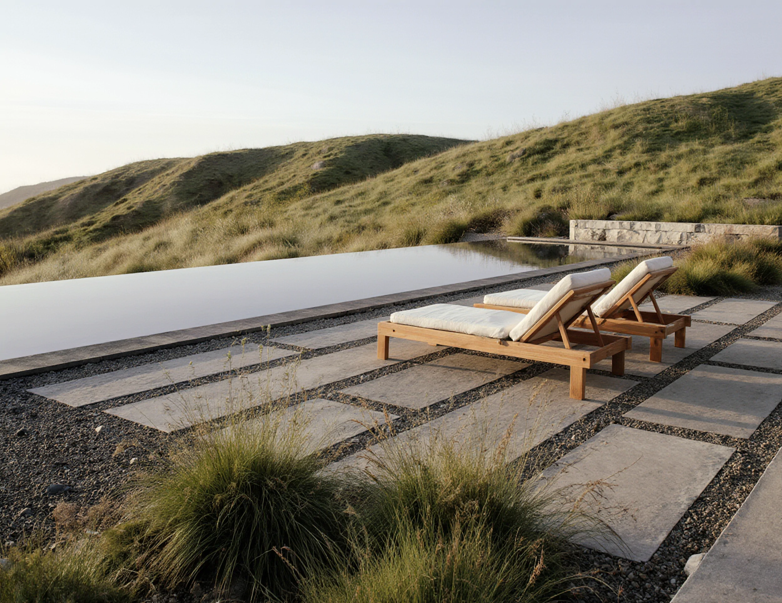 Infinity-edge pool and stone terrace set into soft, grassy hills with expansive valley views.