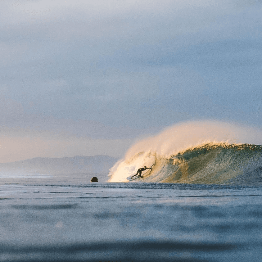 Surfer riding a wave at sunset – surfboard rental in Encinitas.