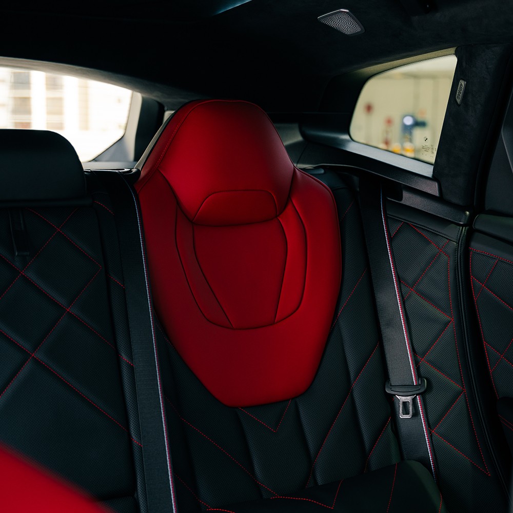 Interior view of the BMW XM rear cabin, highlighting the unique sculptural headliner and ambient lighting.
