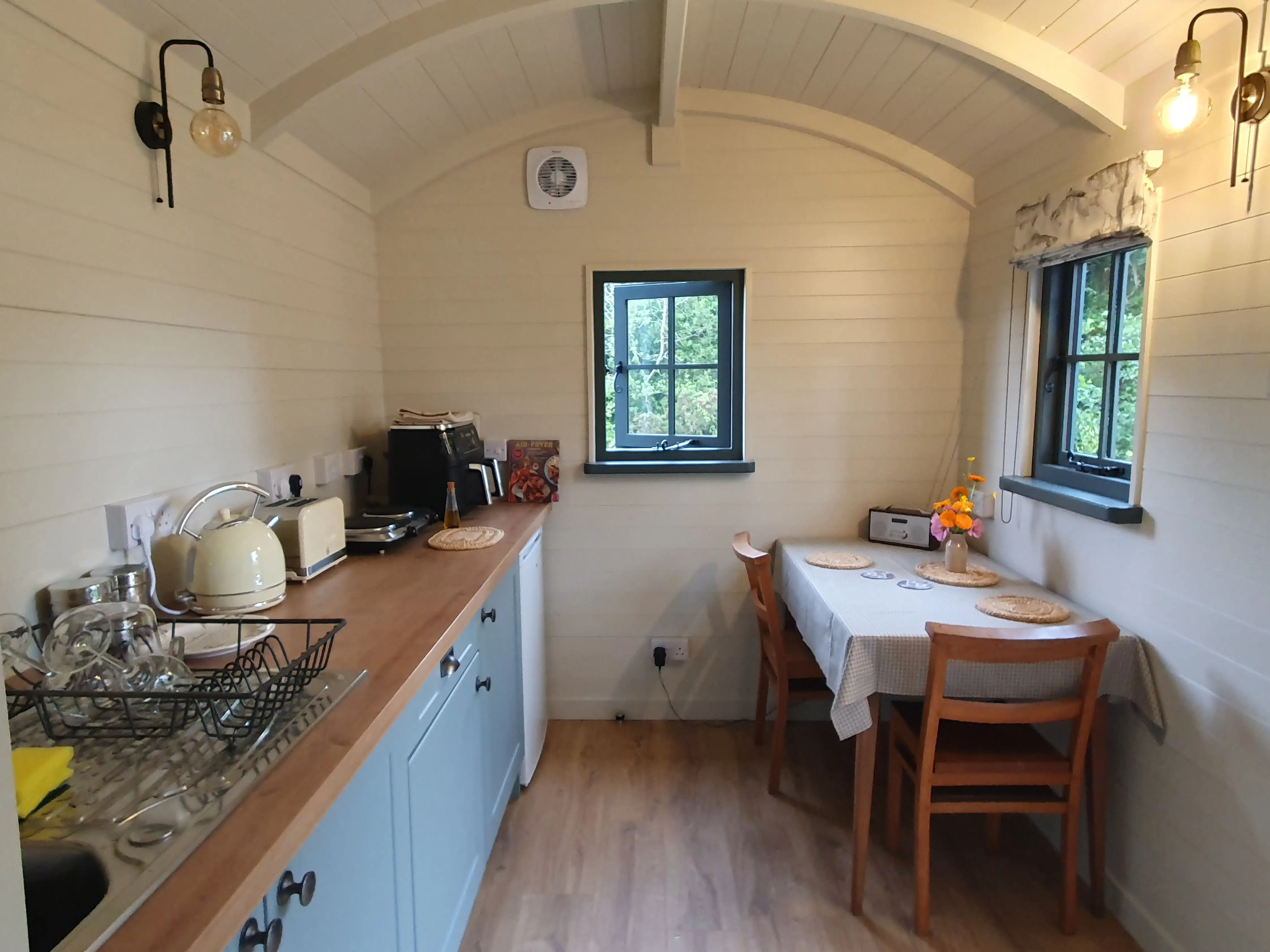 Cozy kitchen space with a wooden table, blue cabinets, and natural light from windows.