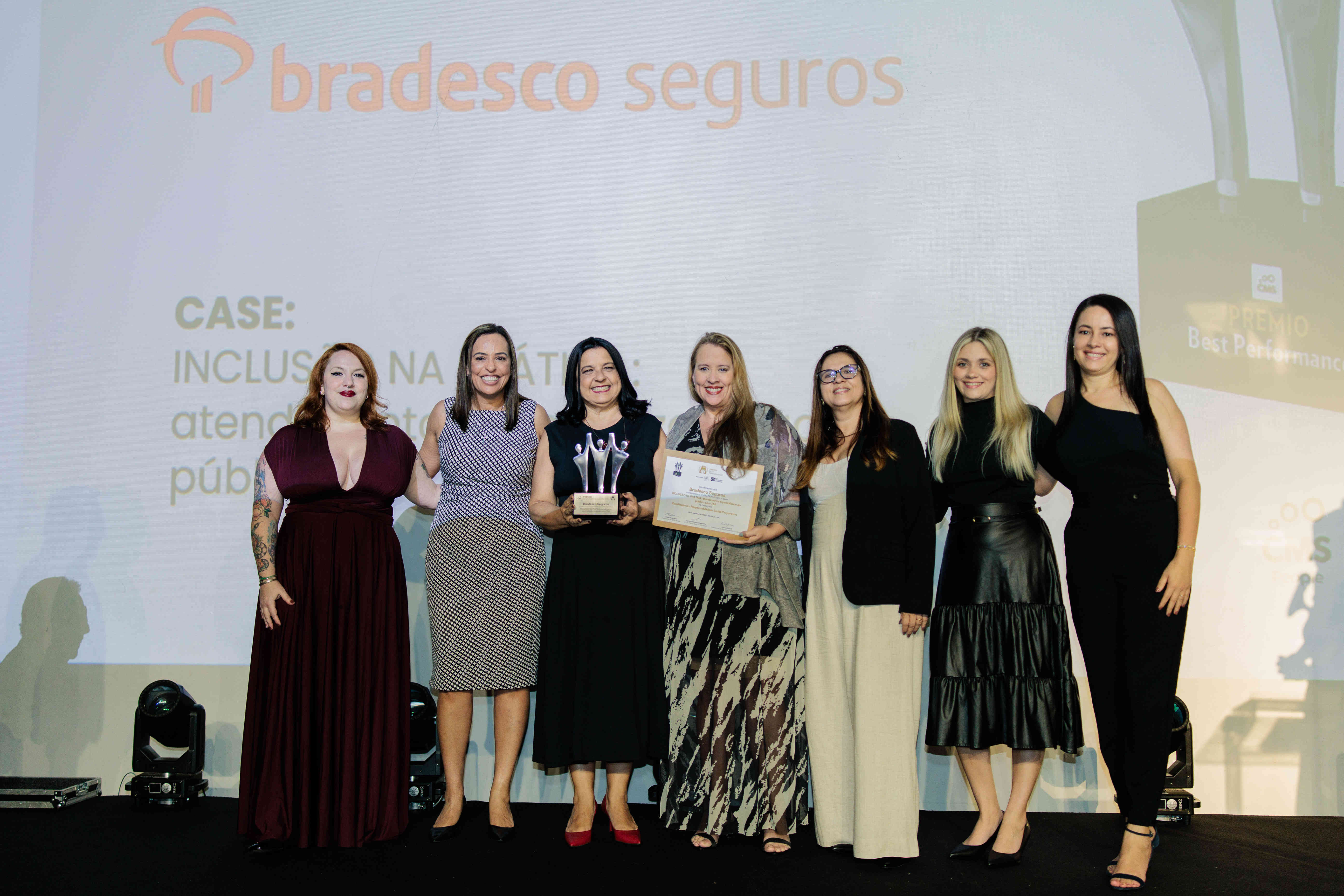 Executivas da Bradesco Seguros posando com troféu prata e certificado no palco do Prêmio Best Performance 2025