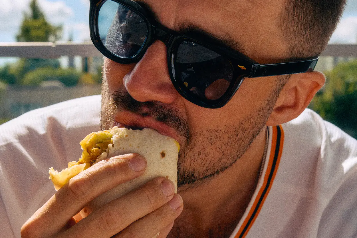 Close-up of man biting into a breakfast burrito.