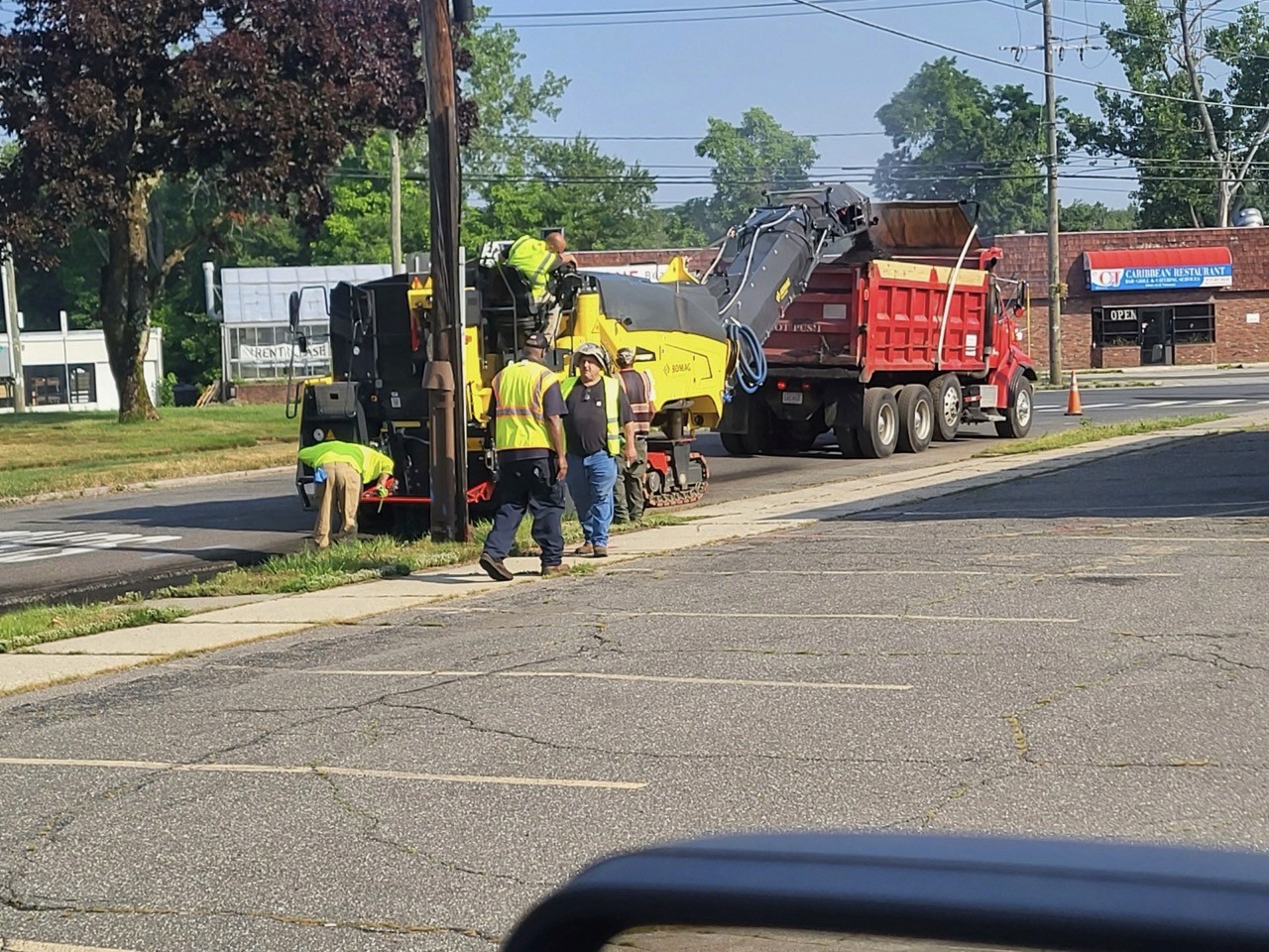 Paving crew and dump truck laying asphalt on a neighborhood street, A&M Construction crew