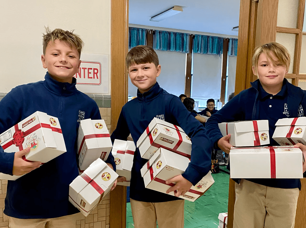 Students holding stacks of gift boxes packed for a service project