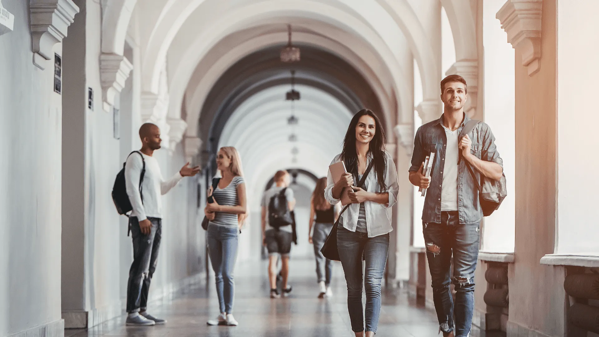 A hallway with a number of students, two of which are walking towards the camera
