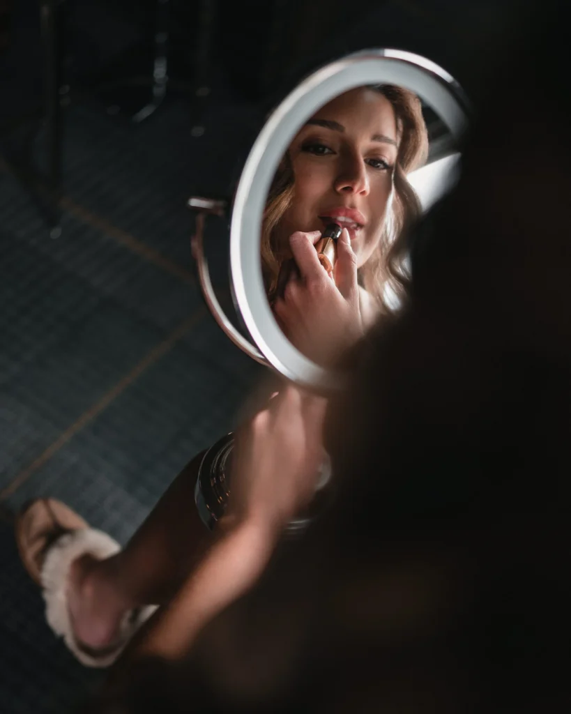 Bride applying makeup in mirror during Aspen Meadows Resort Wedding morning preparations