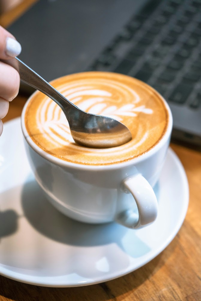 Close-up of a white cup of coffee, with a milk pattern on top
