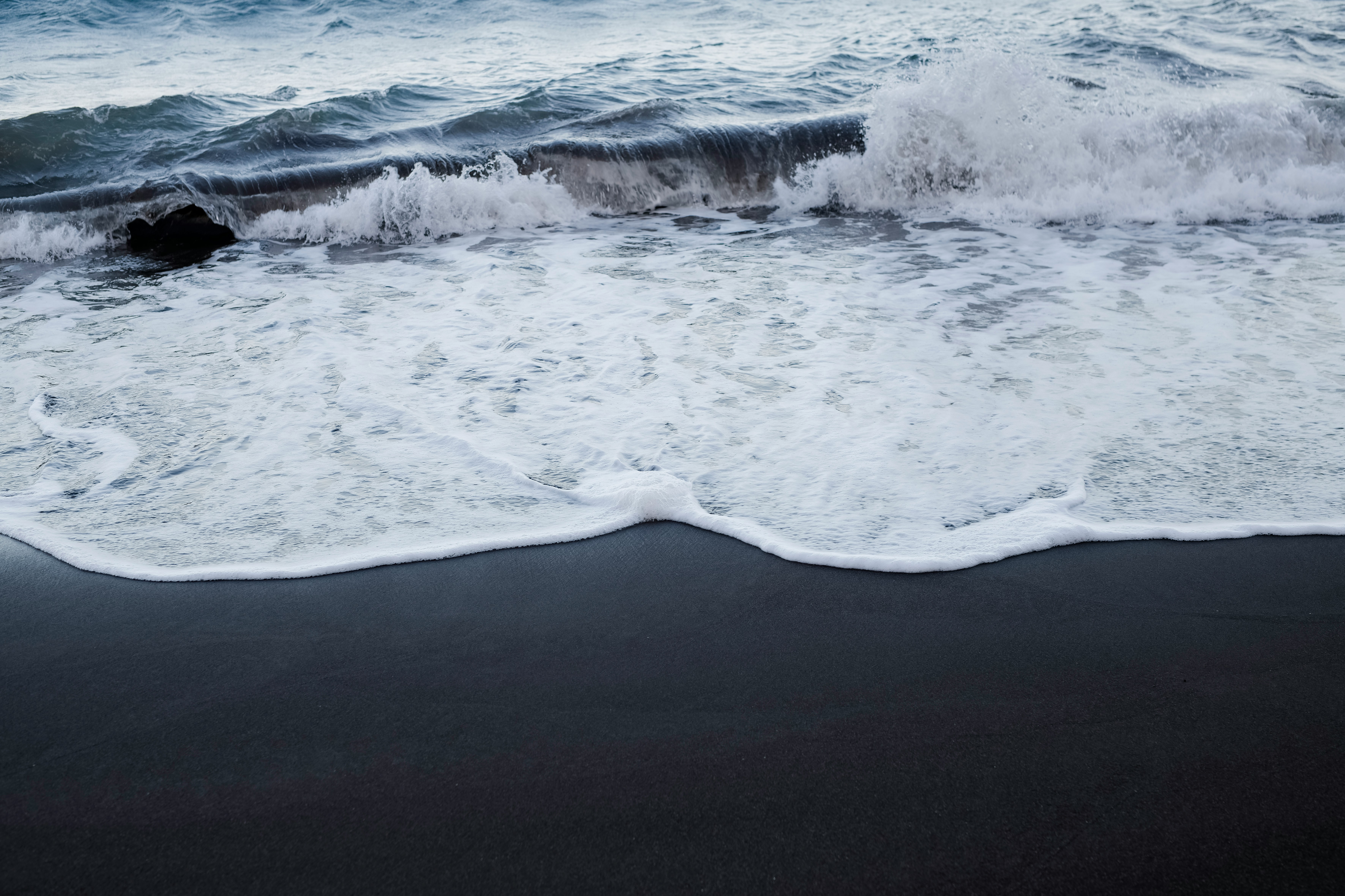 Waves breaking on the shore of a black sand beach in South Iceland.