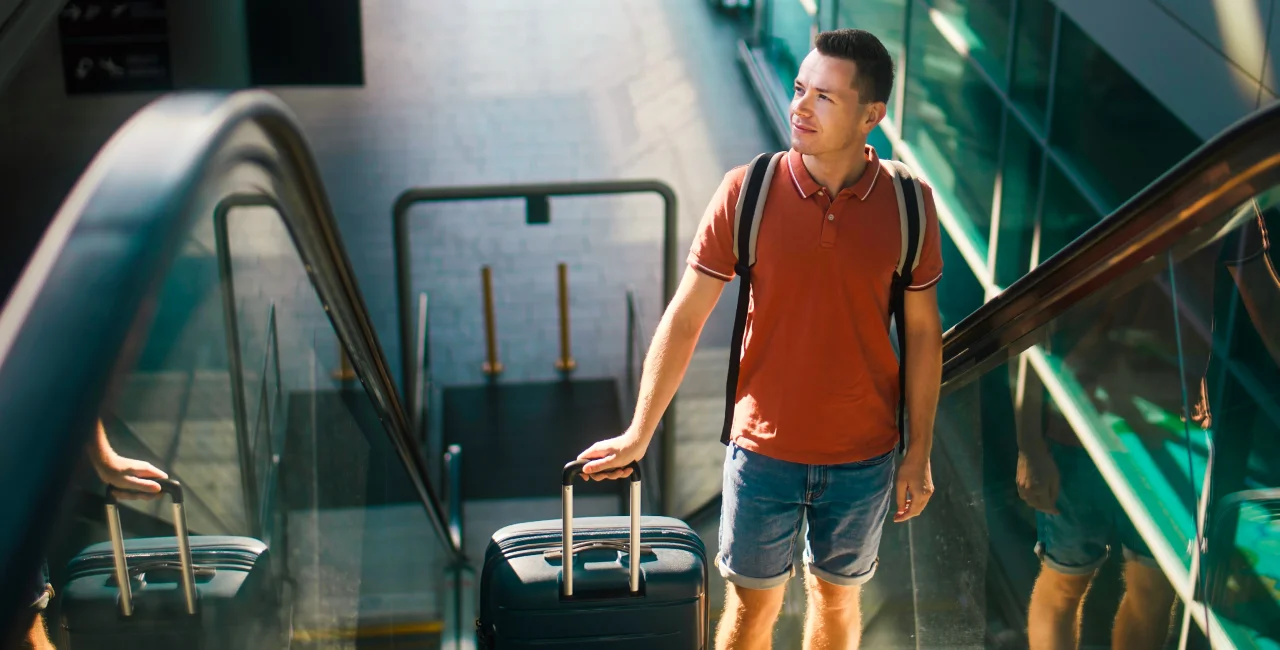 Traveler with luggage at Prague Airport escalator