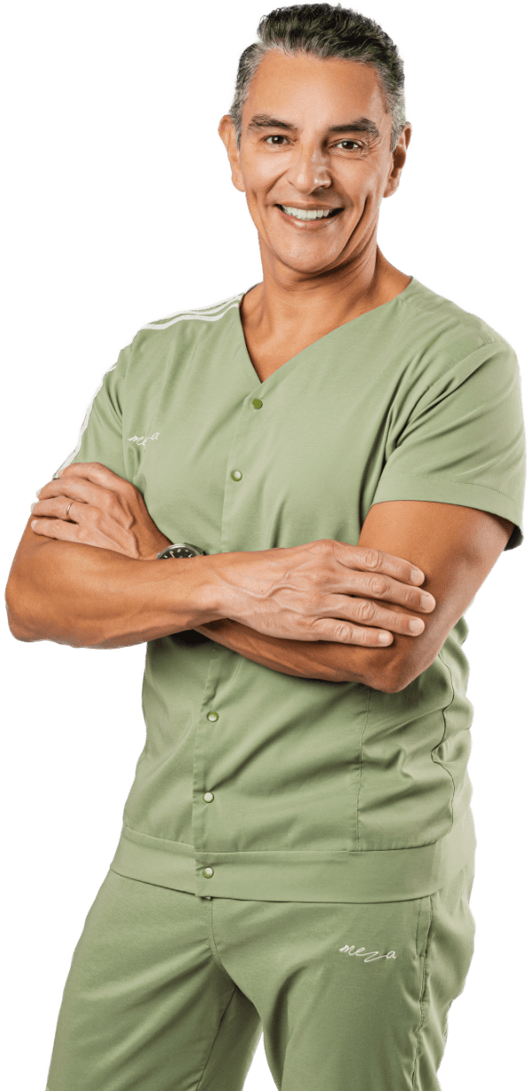 Dr. Meza poses for the camera crossing his arms and smiling, wearing a light green uniform.