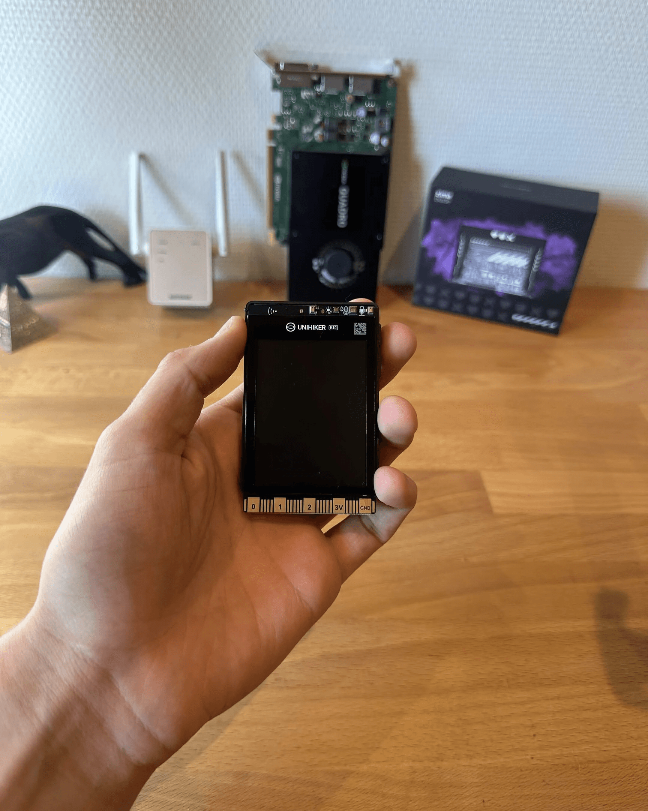 Holding the compact UNIHIKER K10 development board in one hand.