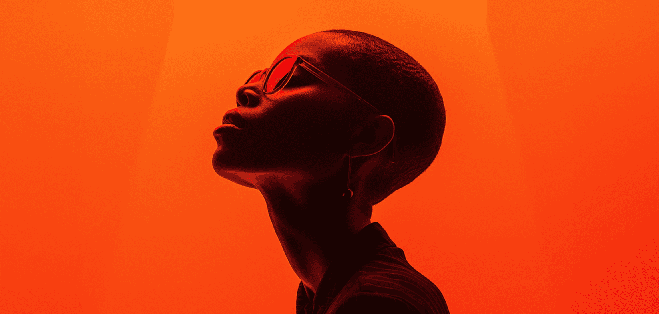 A woman with glasses stands in front of an orange light, creating a warm and inviting atmosphere.