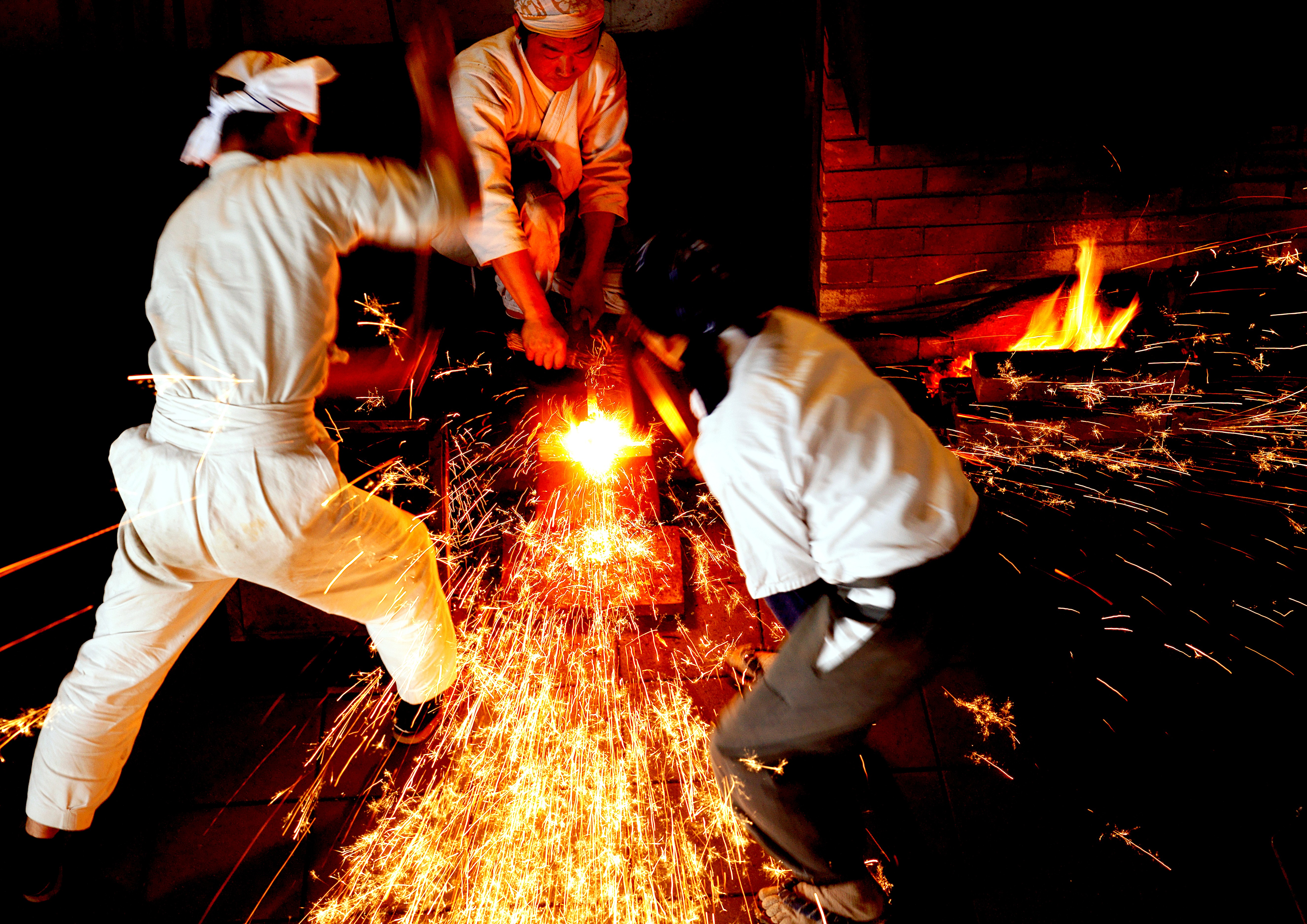 Swordsmiths hammering iron in a team