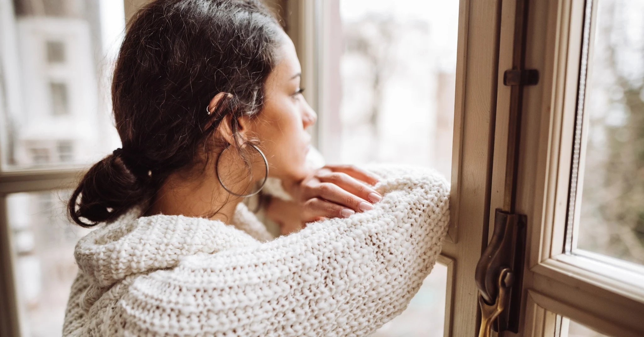 Kvinna tittar sorgset ut genom fönstret.