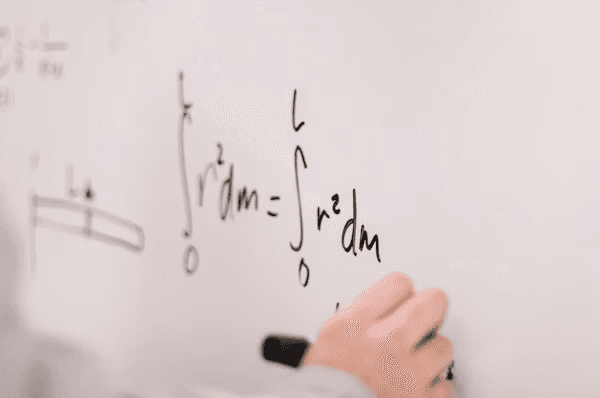 High school student working on mathematics research with a PhD mentor, reviewing equations and data on a laptop