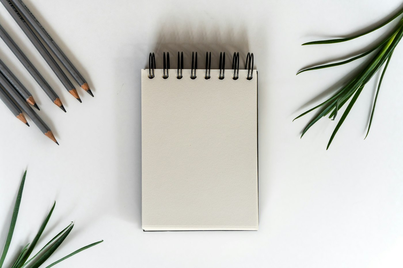 Blank spiral notepad and sharpened pencils on a white desk