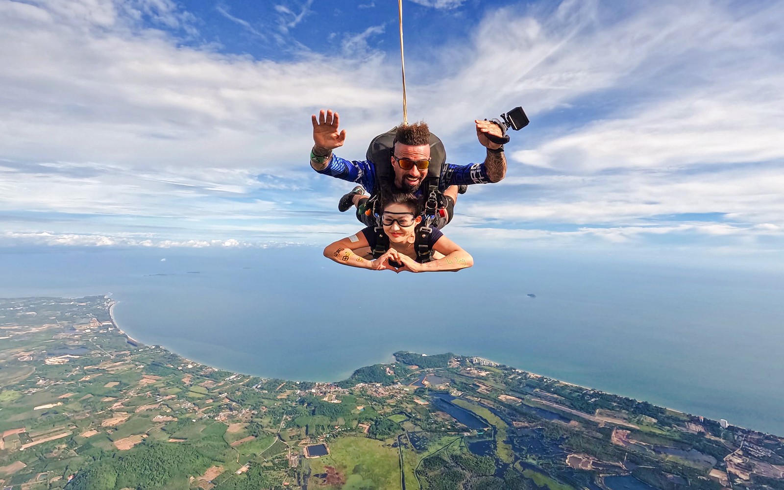 Skydivers above coastline and ocean, capturing breathtaking coastal view.