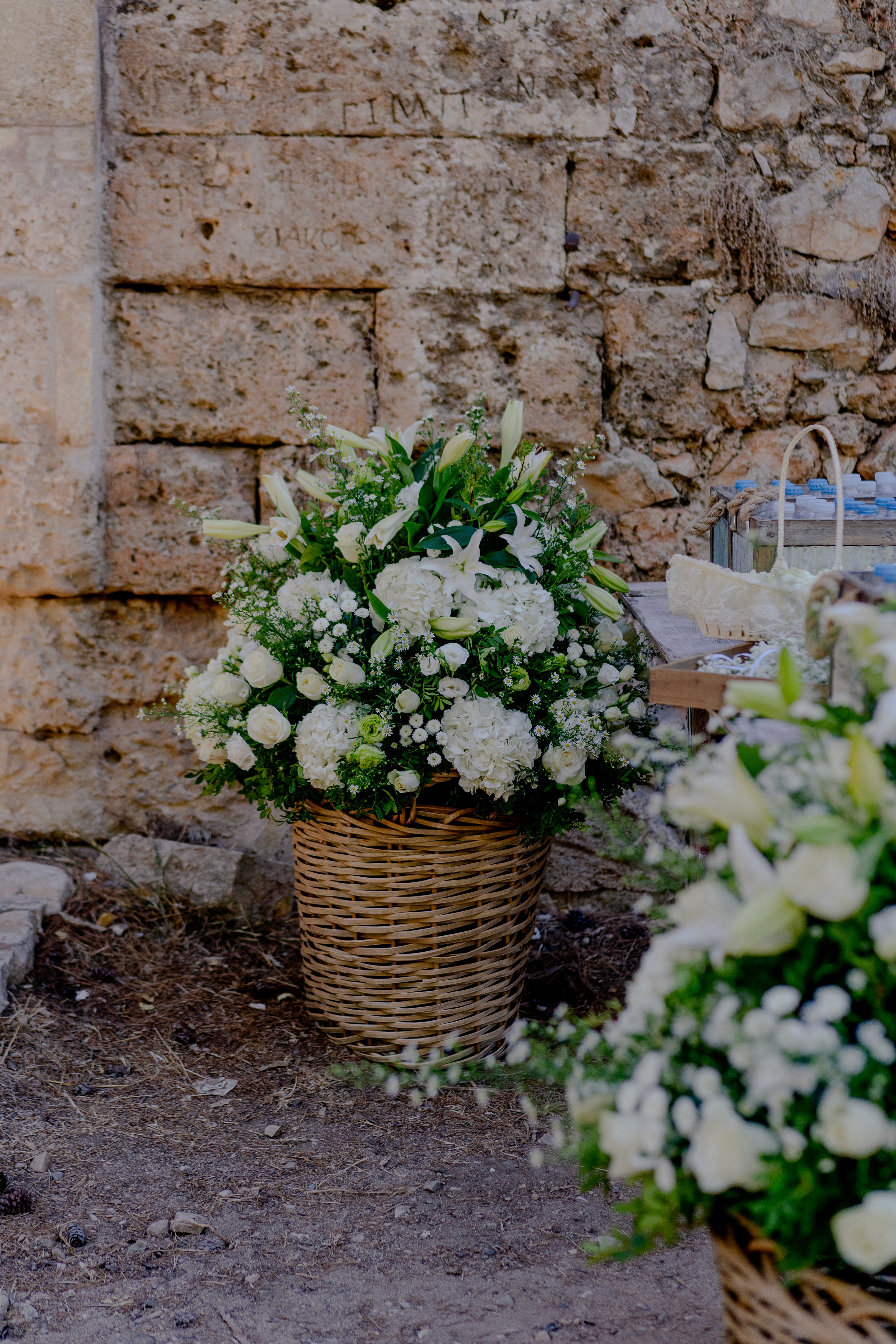 Rustic wedding decoration featuring a wicker basket filled with white lilies and greenery