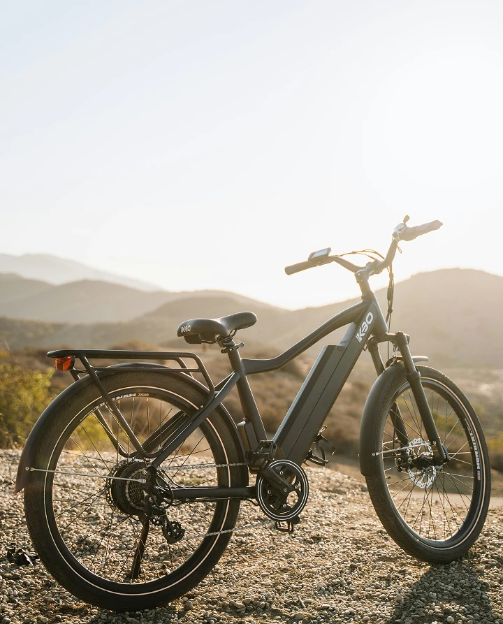 Vélo de ville à assistance électrique (VAE) noir, équipé pour le milieu urbain, stationné au coucher du soleil.
