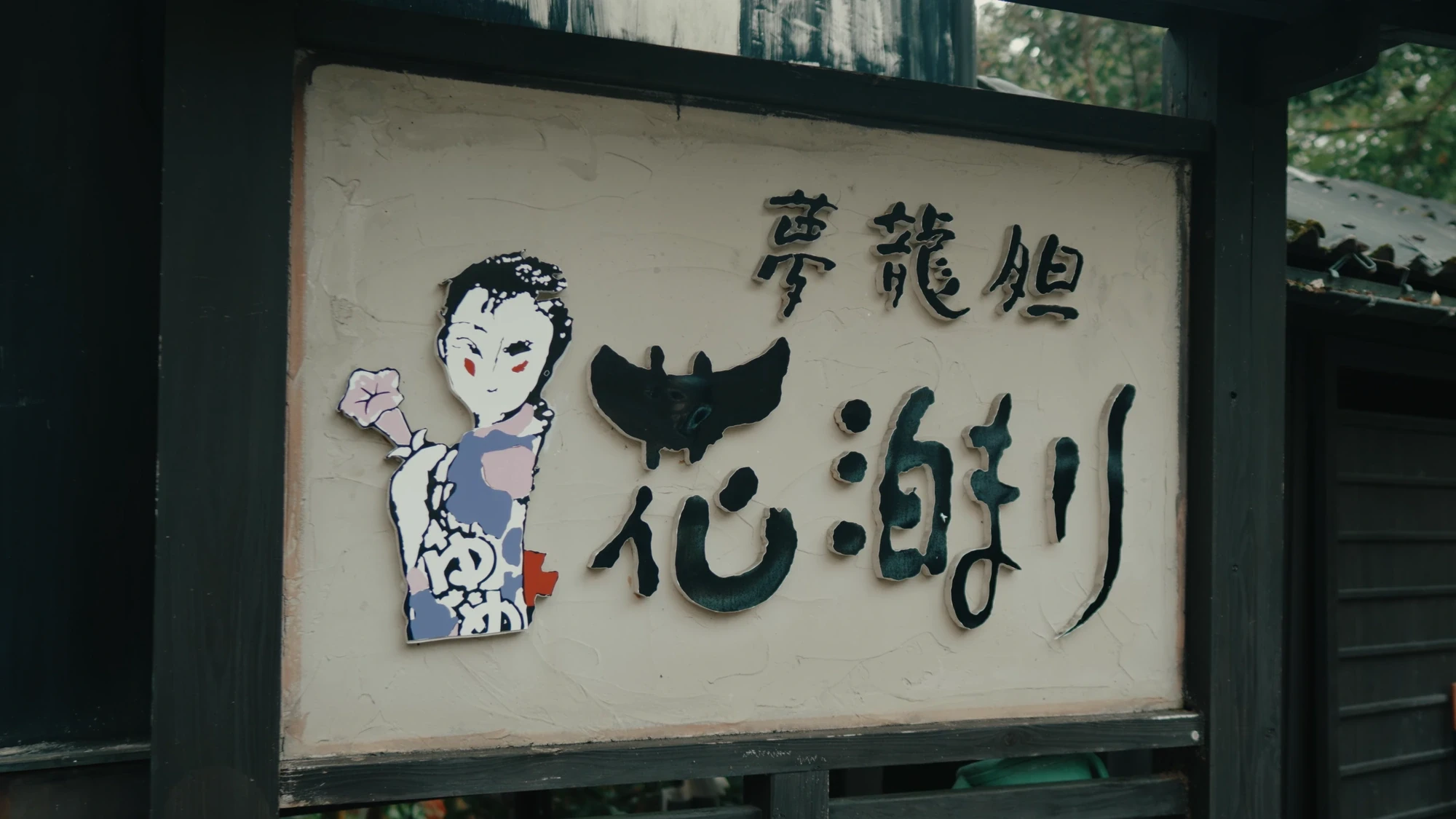 A painted inn signboard at Kurokawa Onsen with a woodblock-style figure