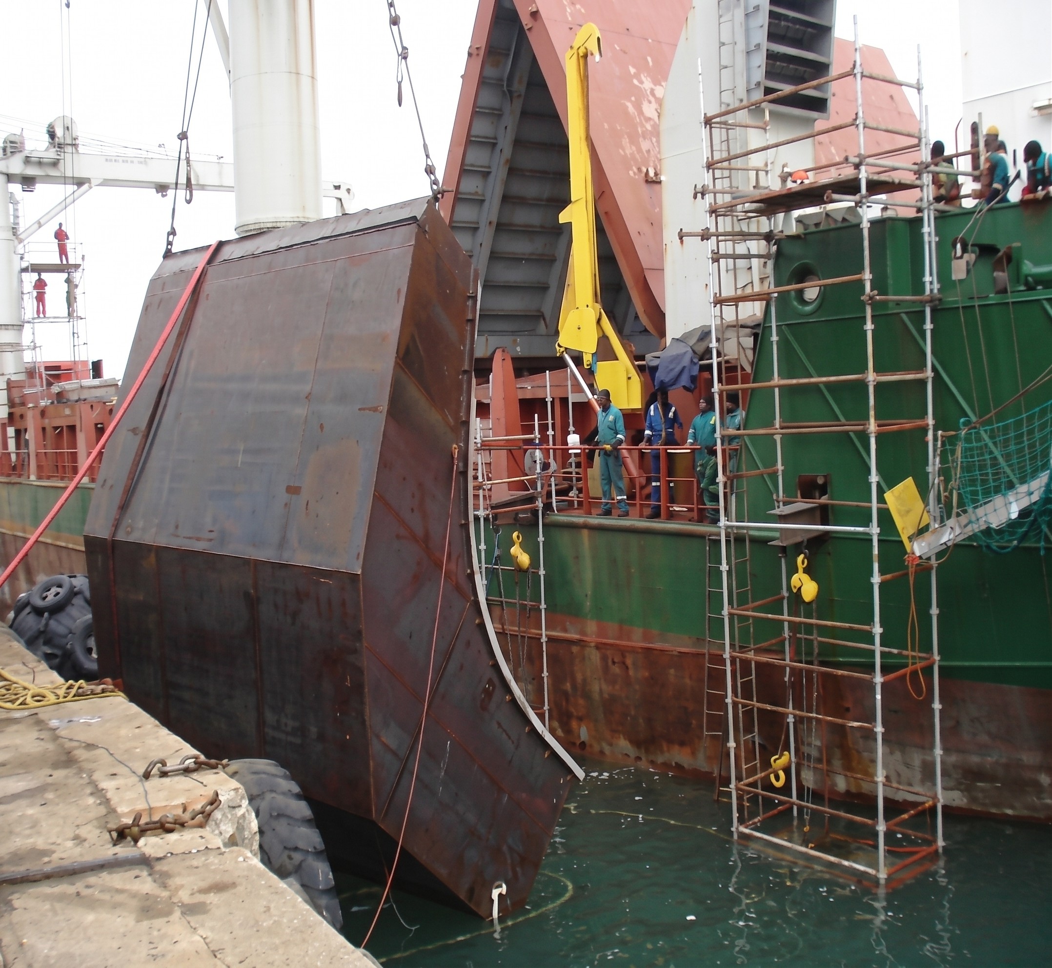 Historical vessel-side repair and scaffolding beside a vessel at berth.