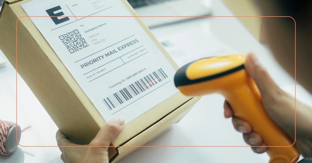 Person scanning a shipping label on a cardboard package with a handheld barcode scanner.