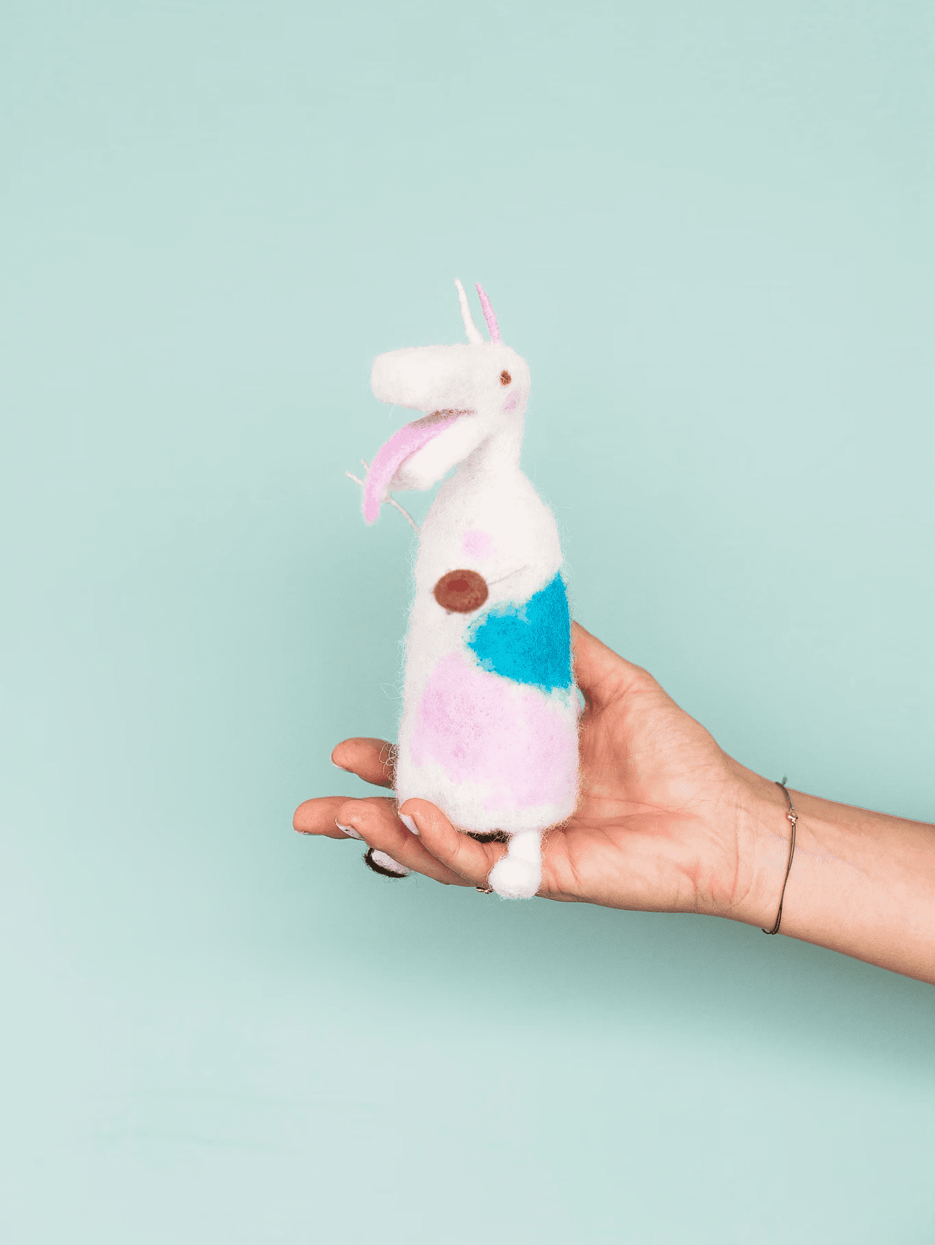 Biela postava turoňa s ružovými a modrými detailmi vyrobená z vlny.