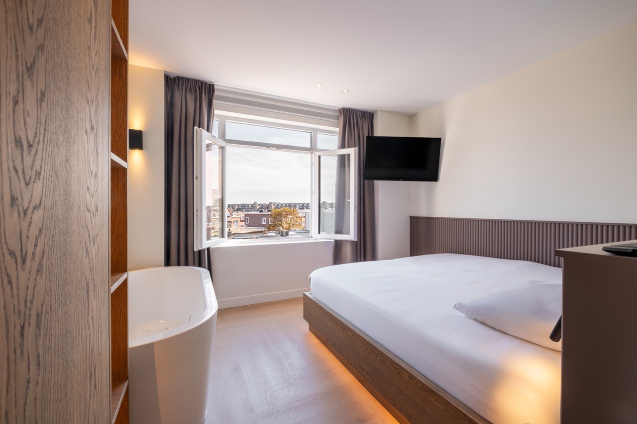 Heldere suite met groot raam en tweepersoonsbed in Scheveningen