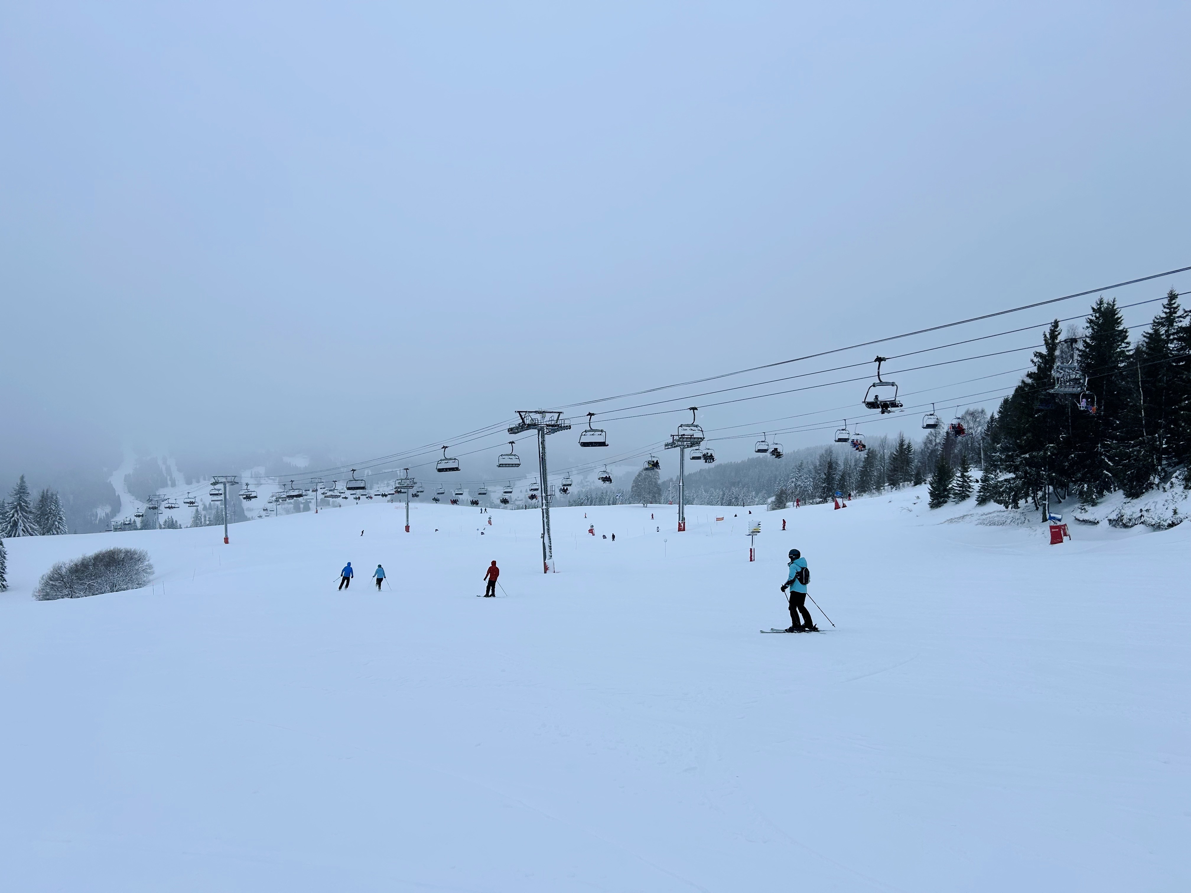 A handful of skiers glide over the snow beneath the Chavannes chairlift in Les Gets.