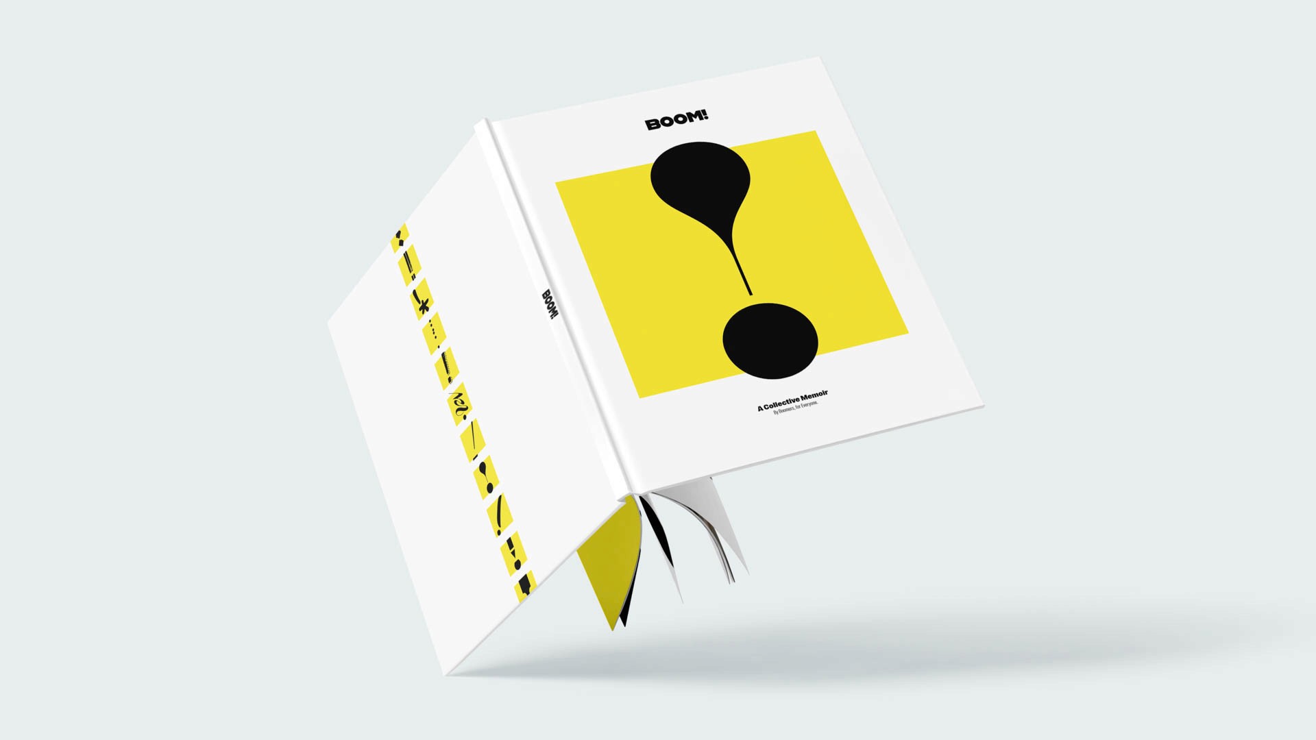 A white book with a yellow square in the center displays the word "BOOM!" in black letters at the top. Below the square, two black circles are positioned, one slightly above the other. Along the left side of the book, yellow letters spell out “BOOM!” vertically. The book is open, revealing its pages and folded pages against a light gray background.