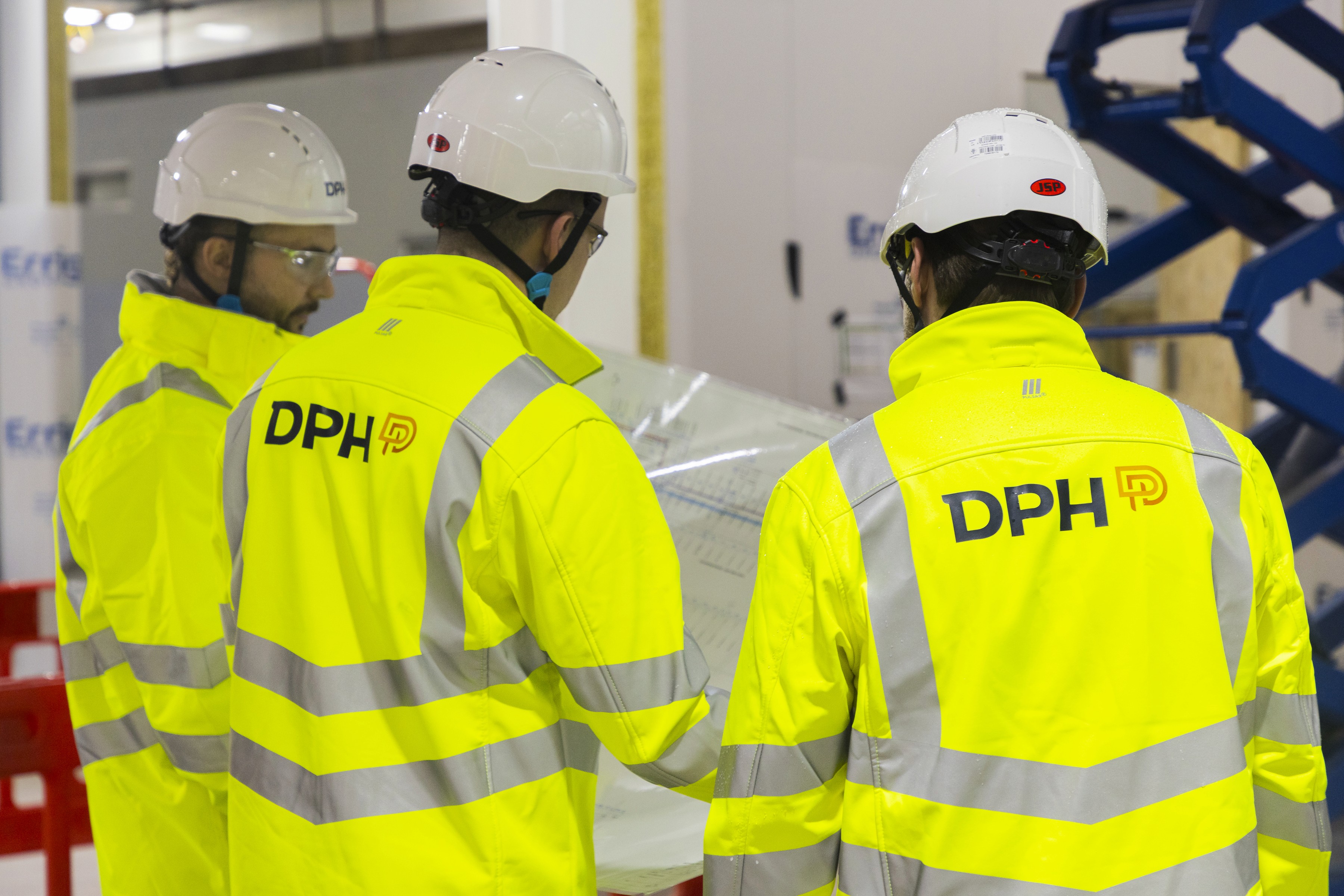 Modern glass building with illuminated facade and trees at sunset