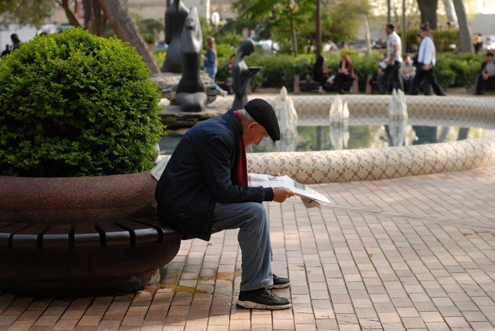 Persona mayor leyendo en una plaza, asociada al APV y su protección en Chile