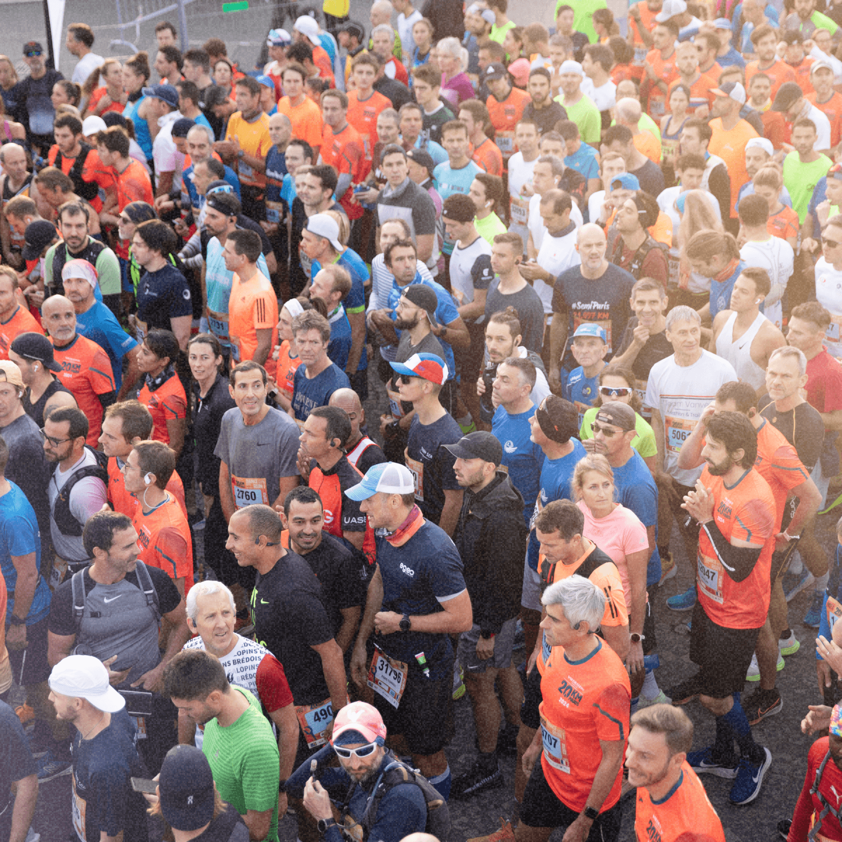 Vue aérienne d'une grande foule de coureurs participant à un événement sportif, portant principalement des tenues de course colorées.