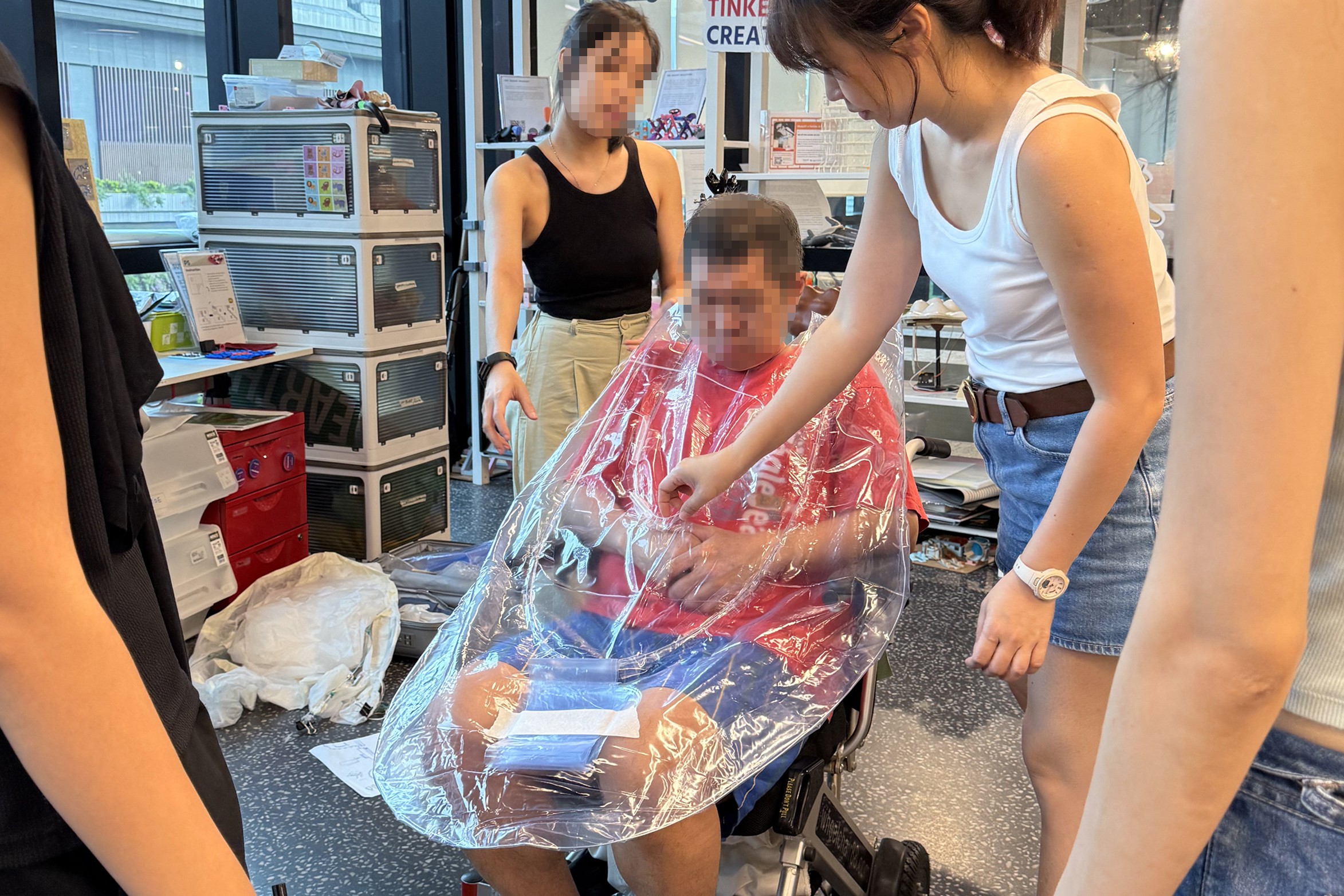 55 Minutes team and caregivers reviewing an early prototype of the wheelchair poncho made from plastic and steel wire