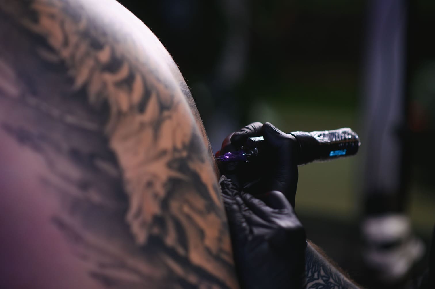 Tattoo artist working on a client’s arm in the studio