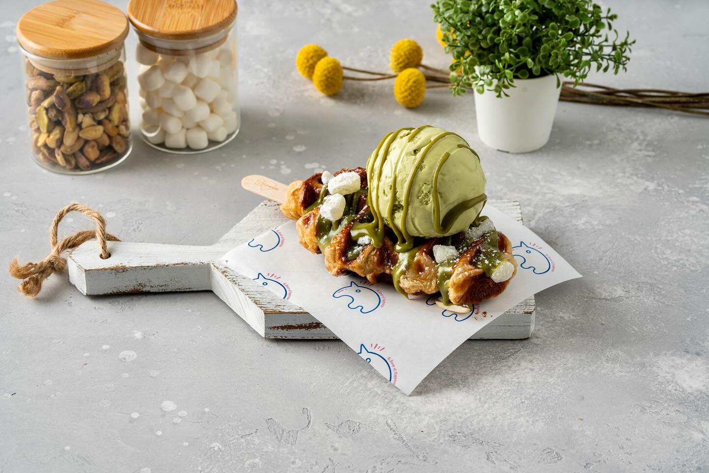 A flaky croffle topped with a luscious scoop of matcha ice cream, drizzled with syrup, and garnished with fresh toppings. Presented on branded paper, this dessert is a perfect fusion of texture and flavor, showcasing Smoove’s signature creations.